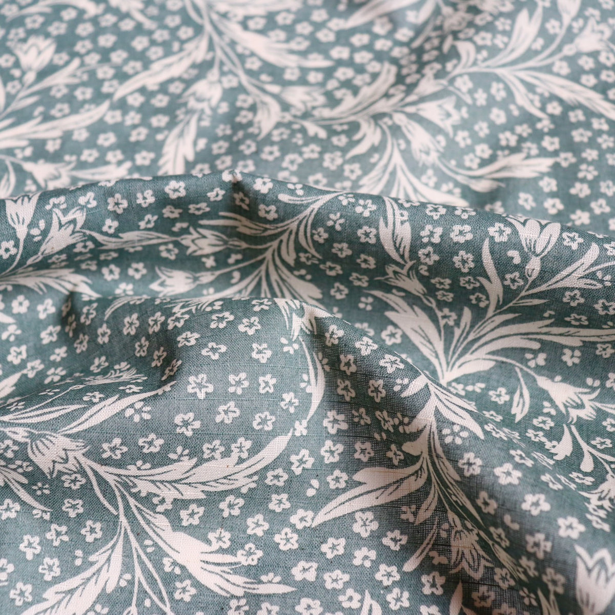 green linen cotton fabric with wispy floral print in woodblock style