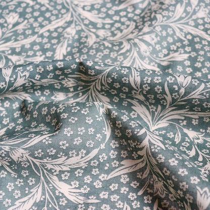 green linen cotton fabric with wispy floral print in woodblock style